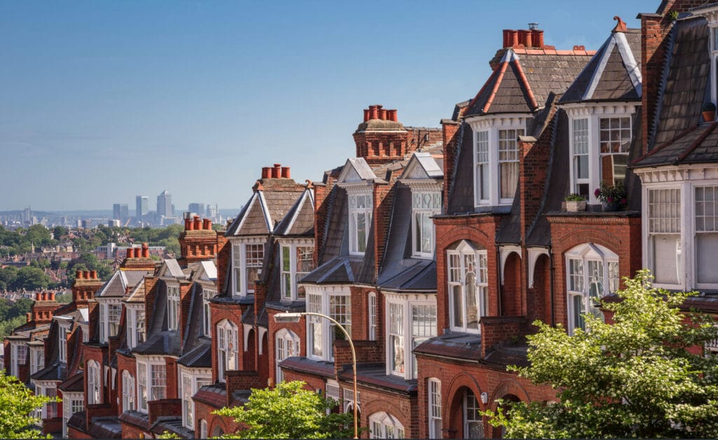 Rows of red-brick houses on a hillside with the London skyline beyond